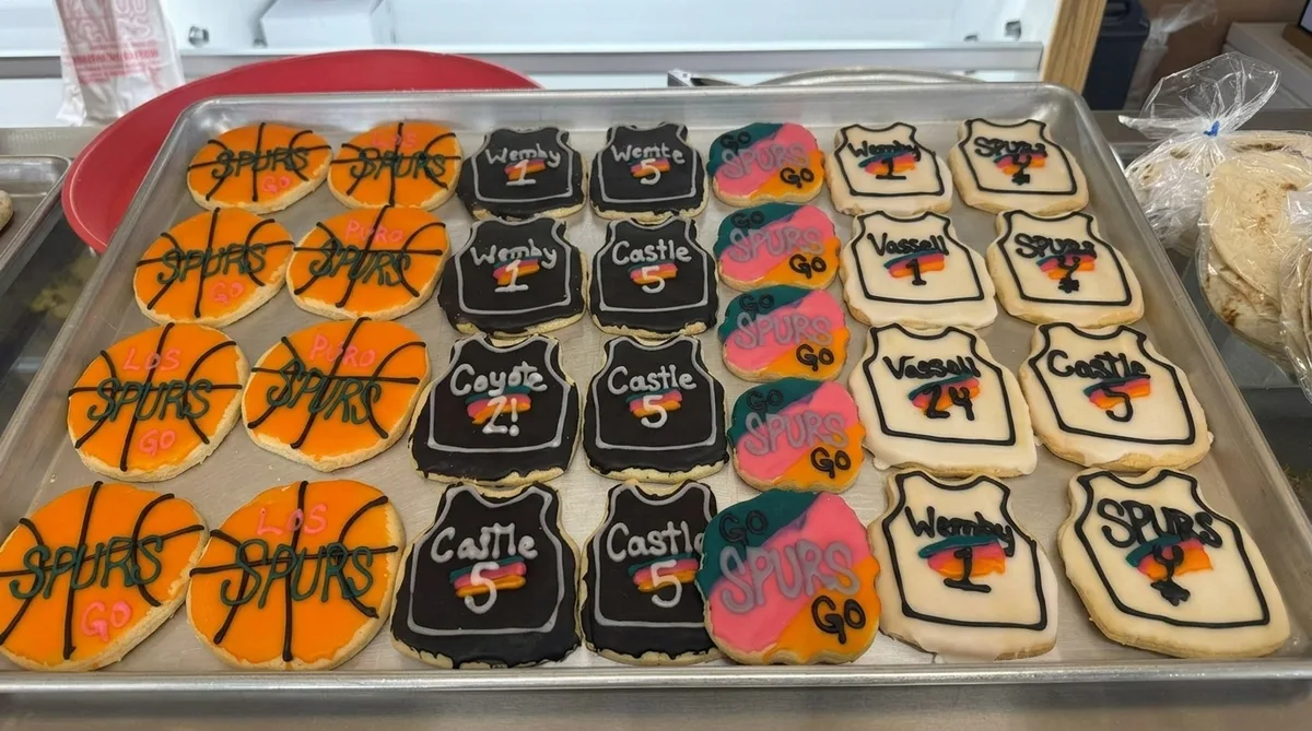 Tray of hand-iced Spurs cookies — orange basketballs, black Wemby and Castle jerseys, Fiesta-color SPURS shapes.
